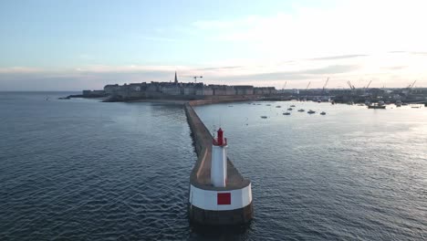 saint-malo lighthouse and pier with city in background at sunset, brittany in france