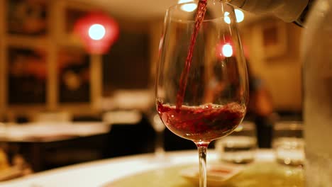 a close-up of red wine being poured into a glass in a warmly lit gold coast restaurant