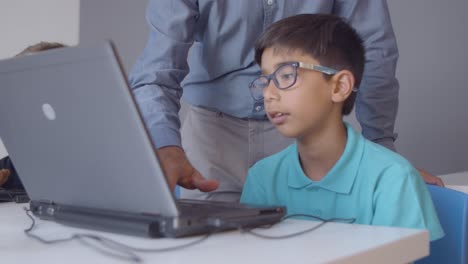 teacher helping worried schoolboy to do task