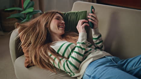 happy girl falling couch making smartphone selfie closeup. woman using cellphone