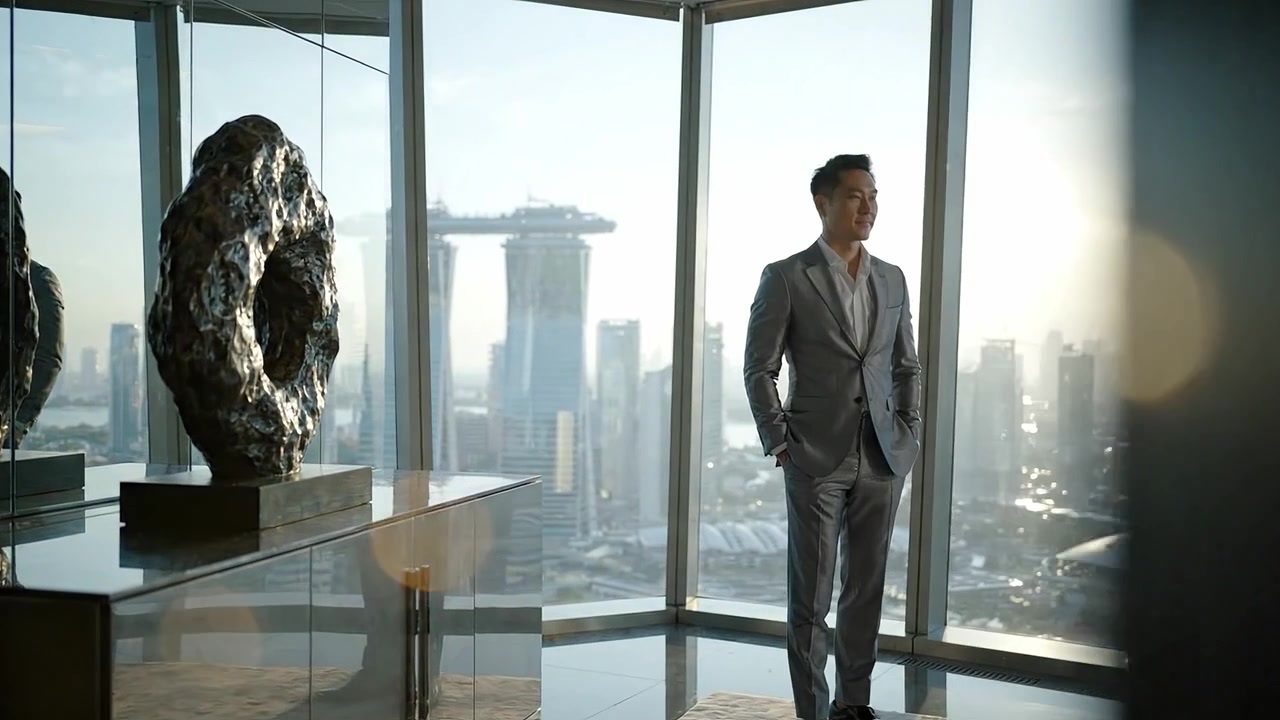 Un uomo elegante in un abito impeccabile sta con sicurezza contro una vista mozzafiato dello skyline, mostrando architettura moderna e un tocco di lusso dall'interno di un grattacielo