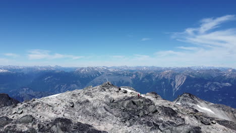 increíble revelación aérea drone tiro de vasto paisaje montañoso con nieve y cielo azul nublado y excursionistas en pacific ranges canadá bc 4k