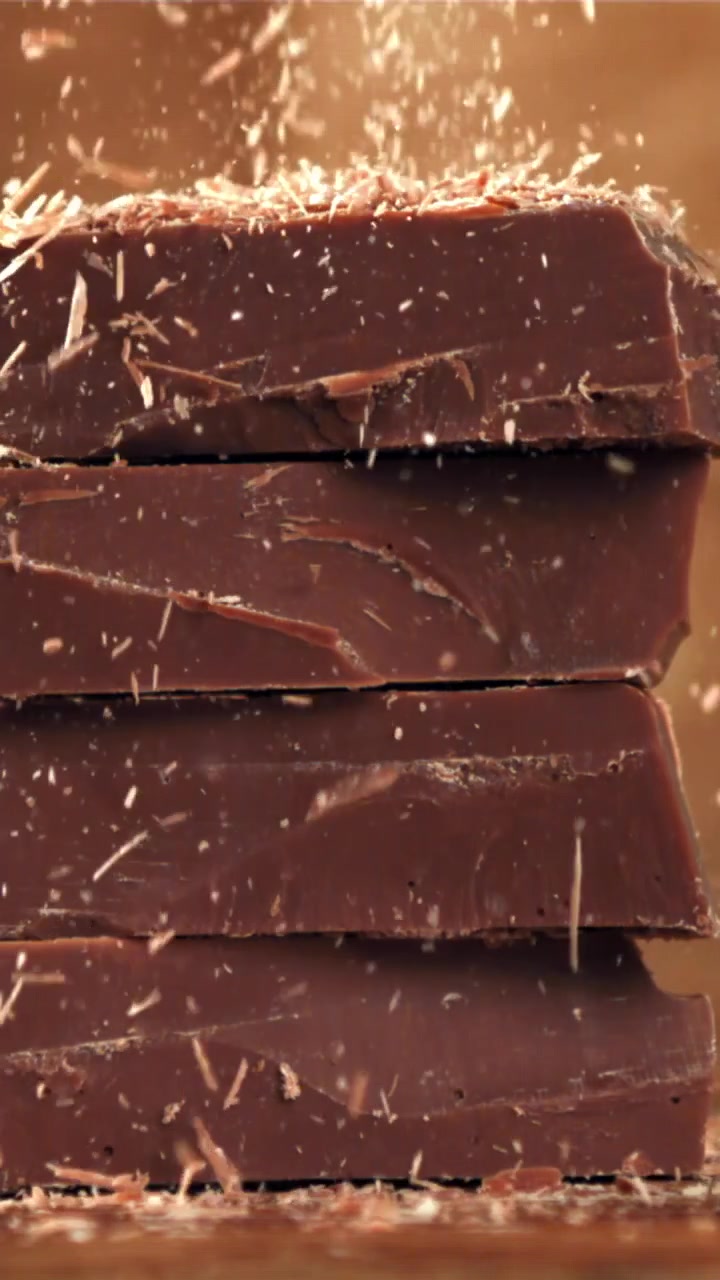 Serutan Cokelat Lezat Jatuh di Atas Batangan Cokelat yang Ditumpuk