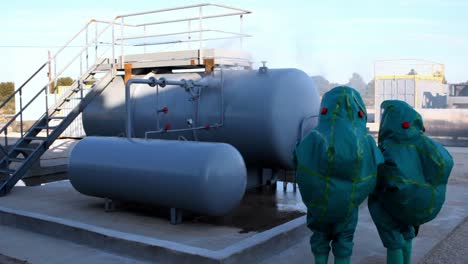 trajes de materiales peligrosos comprobando tuberías con fugas en el área industrial