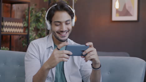 man relaxing on sofa with headphones and smartphone