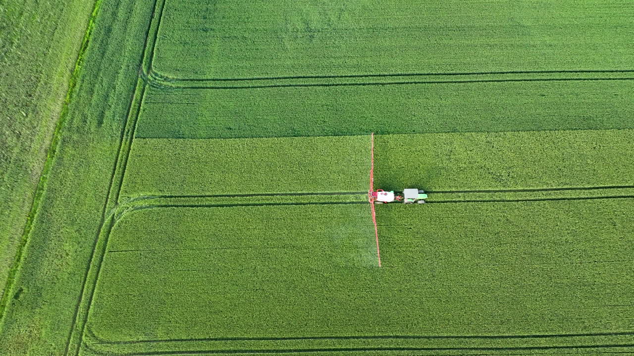 Aerial View of Tractor Spraying Crops in a Green Field