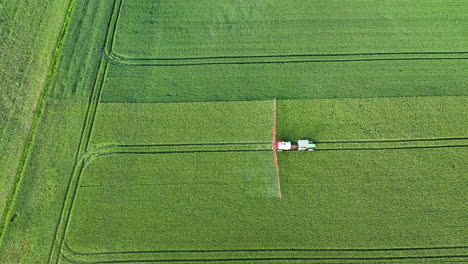 aerial view of tractor spraying crops in a green field