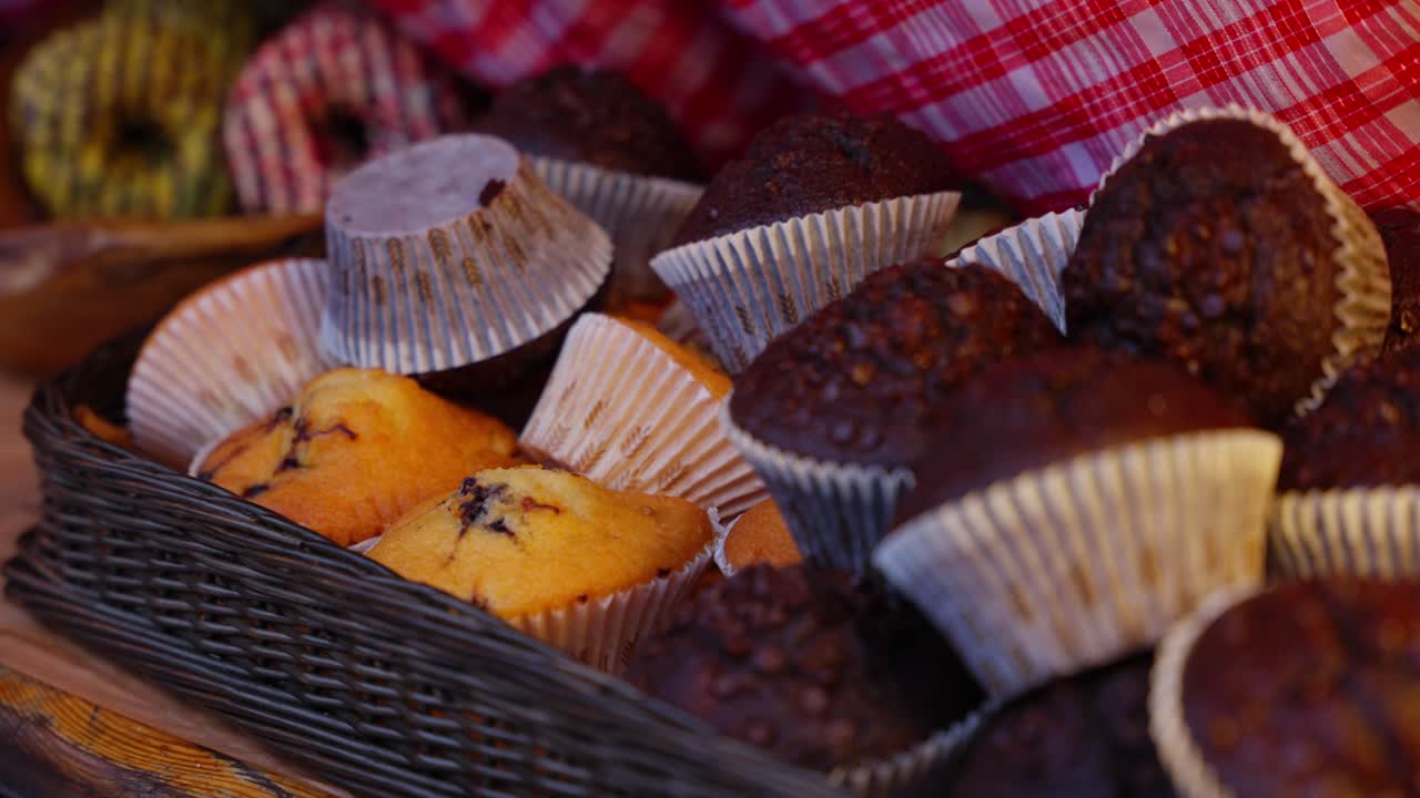 Muffin appena sfornati in un cestino con pirottini di carta su un tavolo rustico, cibo confortevole, ripresa con movimento orizzontale medio-lento verso sinistra