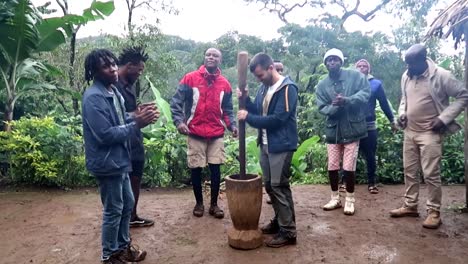 african black chagga people clapping hands, singing and dancing while a tourist man grinds coffee in the middle of them