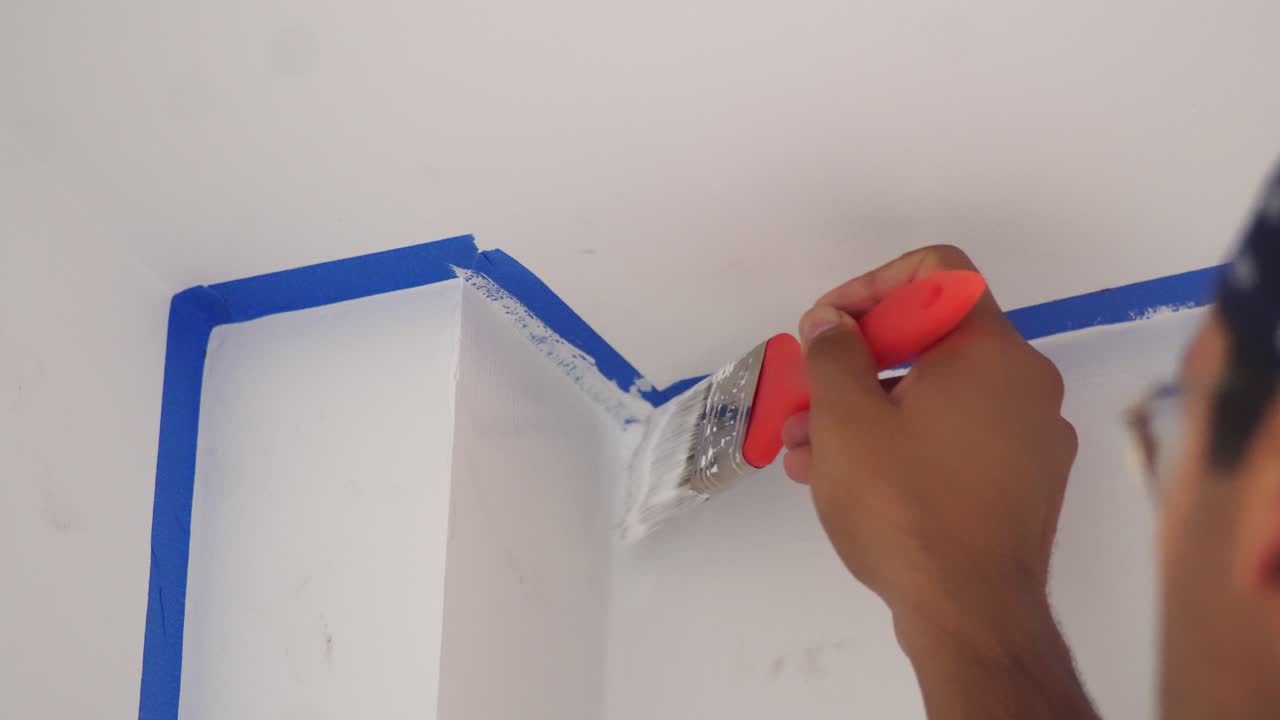 pintor masculino usando un pincel para pintar en la pared - de cerca