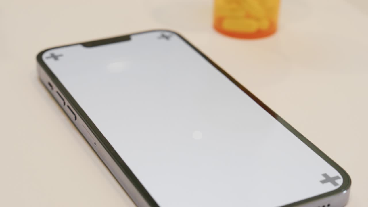 teléfono en el mostrador con una botella de pastillas en el fondo