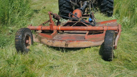 the tractor pulls the grass mowing unit