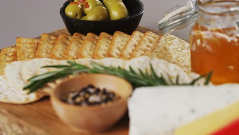 bowl of green olives, spices, crispy biscuits, jam, rosemary herb, cheese and walnuts