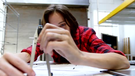 female welder working at desk in workshop 4k