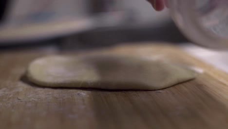 clear glass jar used as rolling pin to flatten tortilla dough on wood board