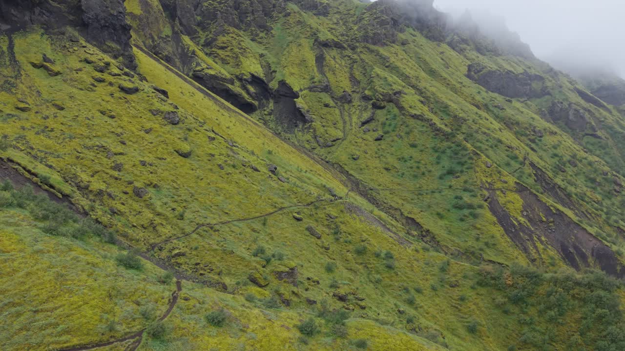 Ripresa aerea su piedistallo che si alza su una verde cresta montuosa ricoperta di muschio per rivelare un vasto e suggestivo altopiano vulcanico