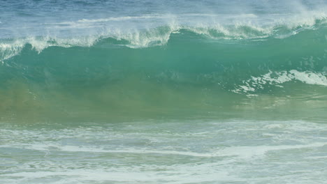 cresta de olas verdes azules y chocando contra la costa en cámara lenta