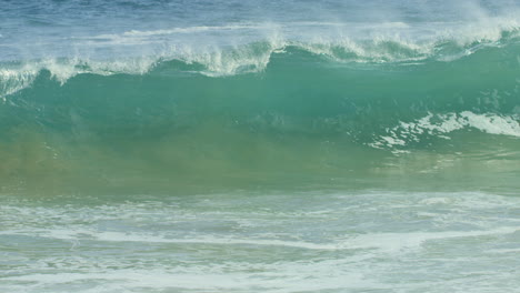 blue green wave cresting and crashing into shore in slow motion