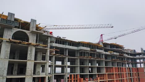 drone view on a new construction site. working process of construction the modern building on the background of two big cranes in the city.