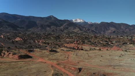 Rising-Drone-footage-over-Red-Rocks-open-space,-with-a-view-of-the-snow-capped-mountains,-in-Colorado-Springs,-Colorado