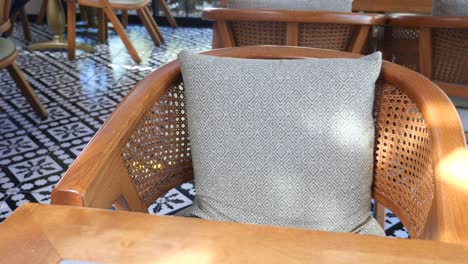 silla de madera con mimbre y almohada en un café