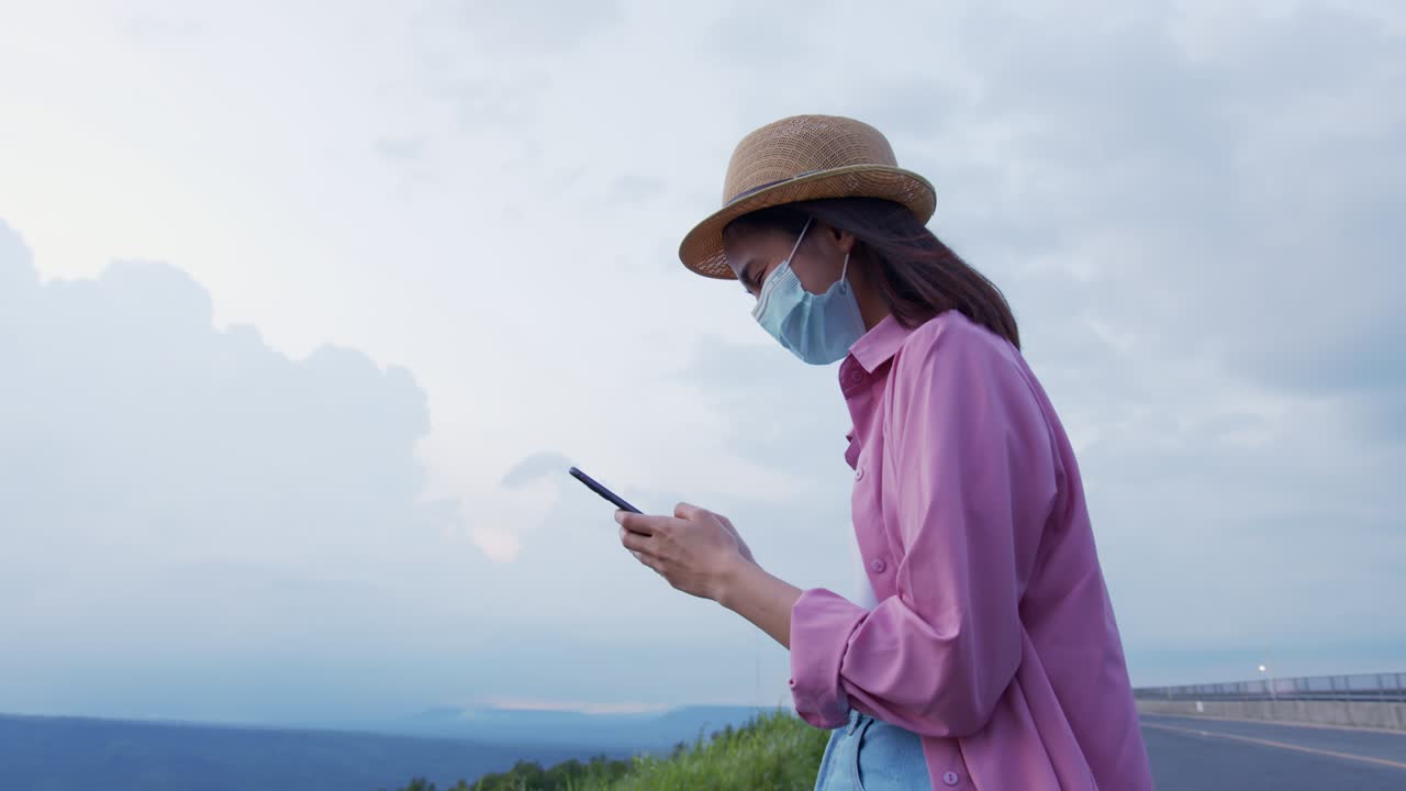 tiro de mano: mujer turista sosteniendo un teléfono de pantalla verde por la noche y una mujer usando una máscara para prevenir enfermedades.
