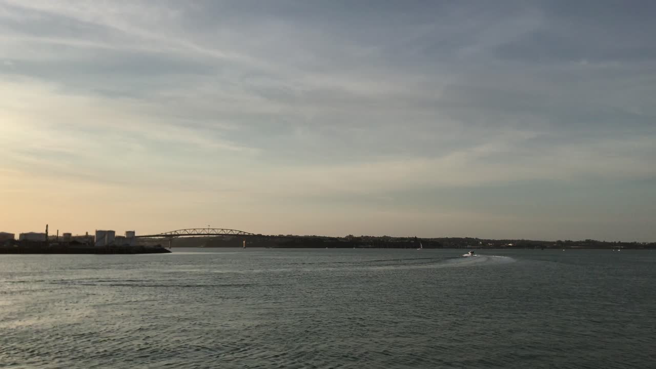 Small yacht heading towards the bridge on the waterfront during a calm evening in Auckland New Zealand