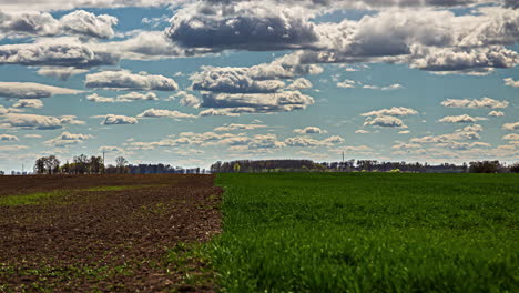 Sonnige-Frühlingswolkenlandschaft-über-Wachsenden-Und-Neu-Gepflanzten-Ackerlandkulturen-In-Der-Europäischen-Landschaft---Zeitraffer