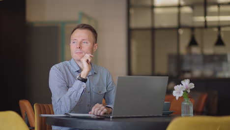 thoughtful serious young man student writer sit at home office desk with laptop thinking of inspiration search problem solution ideas lost in thoughts concept dreaming looking away