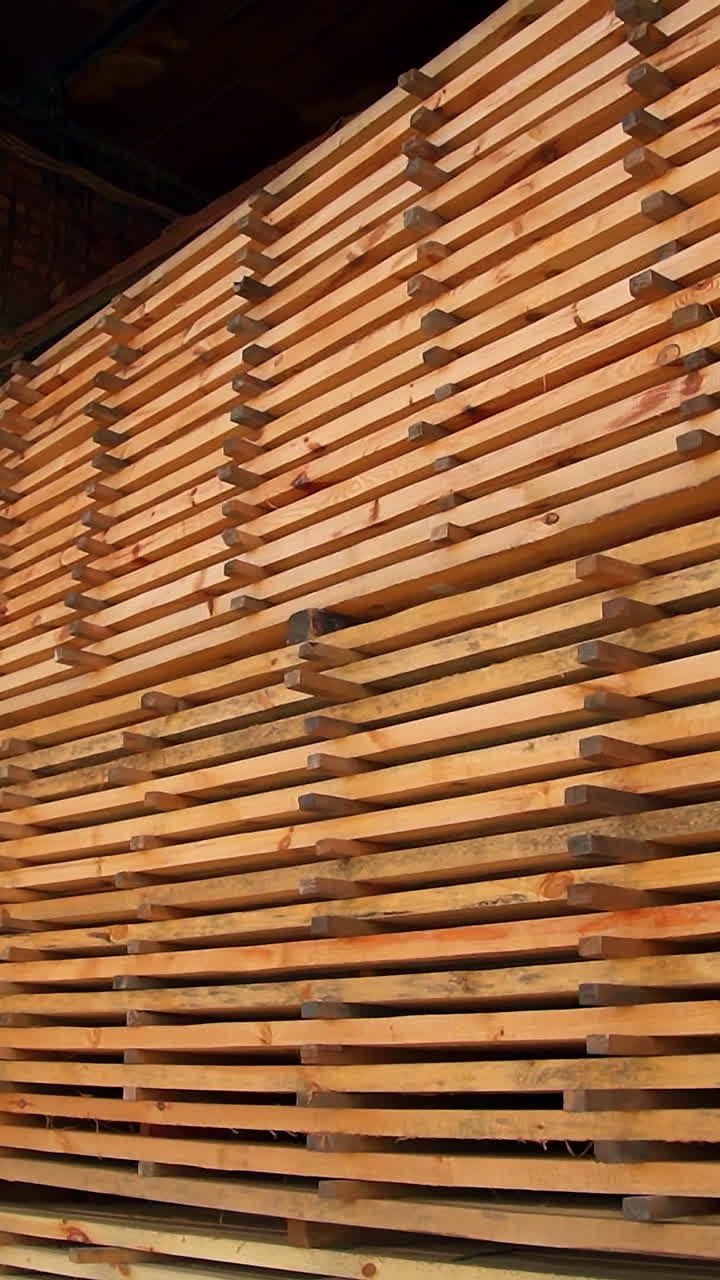 The pile of timber bricks stored in the warehouse. Materials prepared for wood products manufacturing. Vertical video