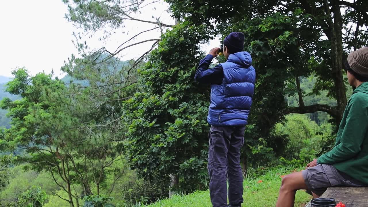 Adventurous friends exploring lush green mountains with binoculars for seeking new horizons