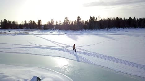 Descenso-Aéreo,-Toma-De-Seguimiento-De-Un-Anciano-Solitario-Caminando-Sobre-Un-Lago-Helado-En-Invierno,-En-Laponia,-Finlandia