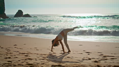 active girl making gymnastics elements in ocean waves sunny day vertical shot