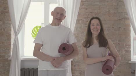 old female and male with a yoga mat looking at camera