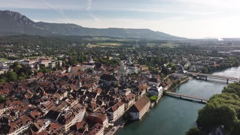 Aerial view of Solothurn, Switzerland, where the winding Aare River cuts through the historic old town with its dense cluster of red-tiled rooftops and iconic church spires