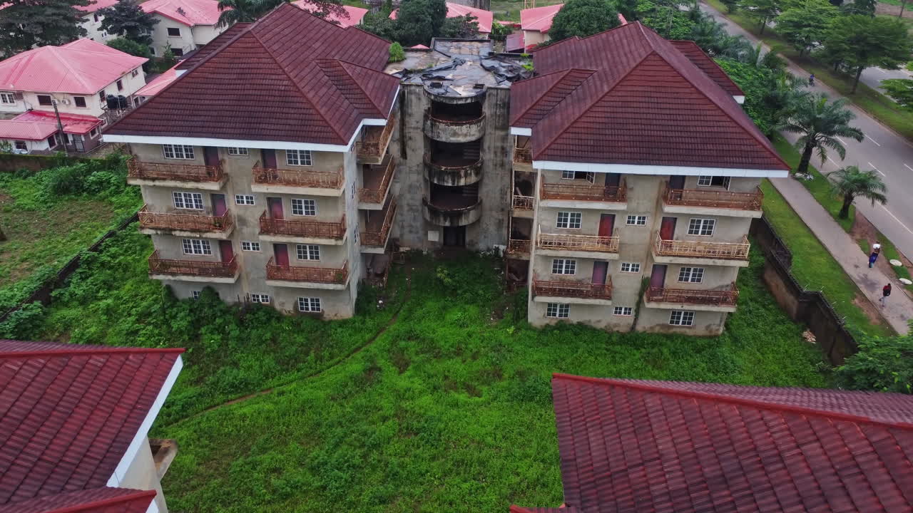 Drone flying towards an old and neglected apartment building in Nigeria, Africa