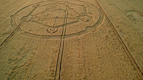 wiltshire wheat field countryside crop circle molecular pattern aerial view rural scene low forward tilt down at sunset