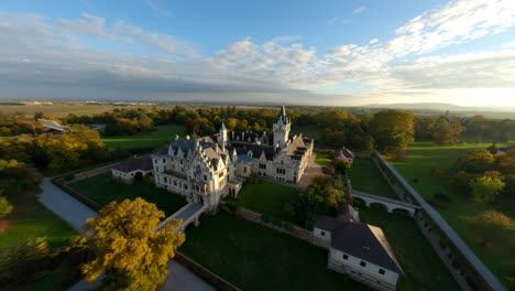 dynamic, fast descending aerial shot of painterly grafenegg castle in warm evening autumn sun