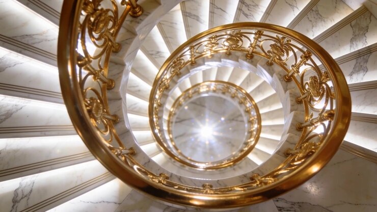 Descending camera revealing spiral marble staircase at lobby, showing gold balustrade, center light