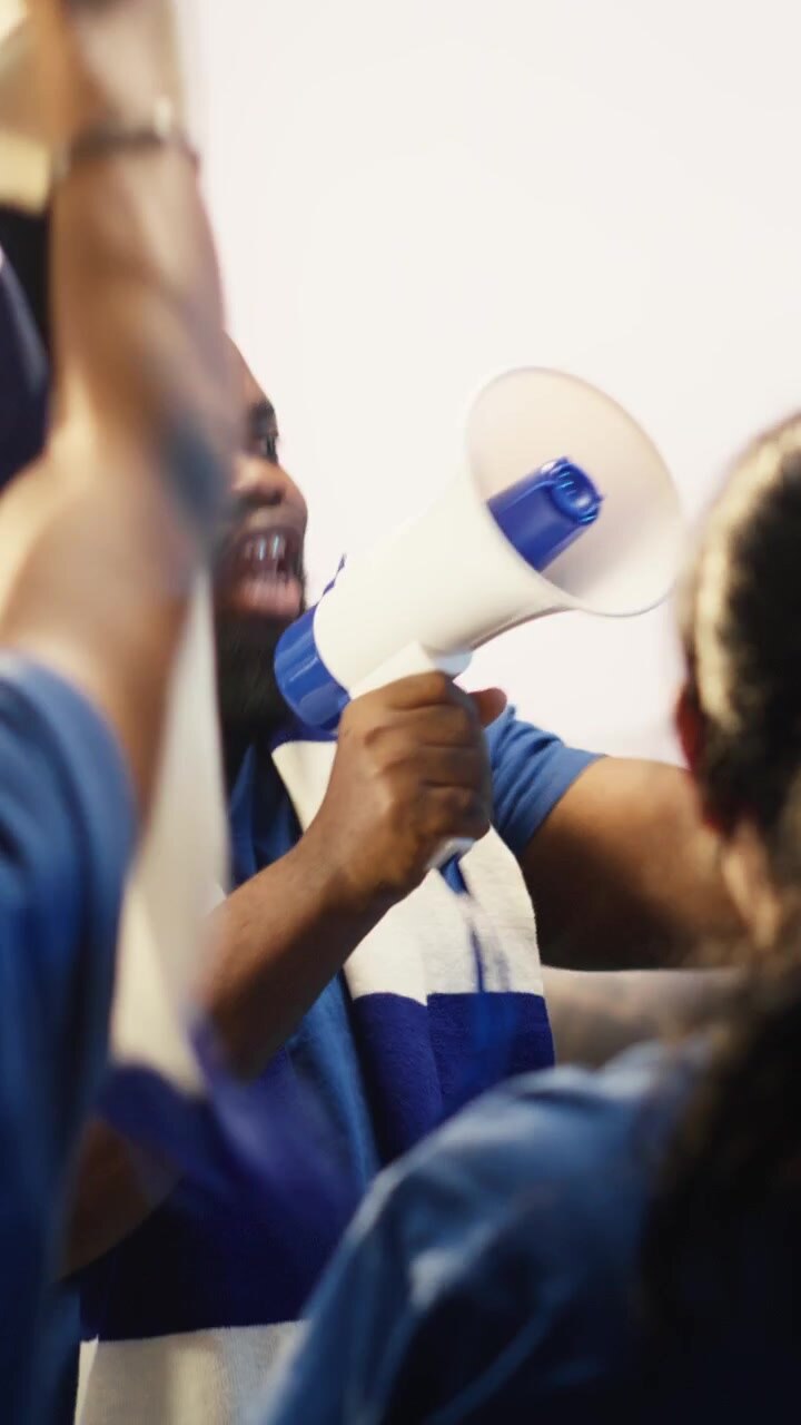 Vertical video Close up of football fans in blue team shirts creating stadium atmosphere