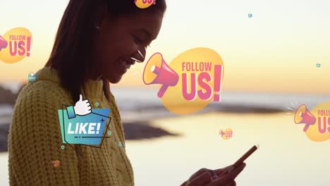 animation of follow us over midsection of smiling biracial woman using smartphone at beach