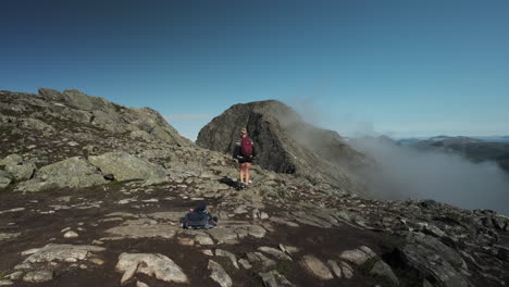 backpacker woman hiking on romsdalseggen ridge in norway - wide shot
