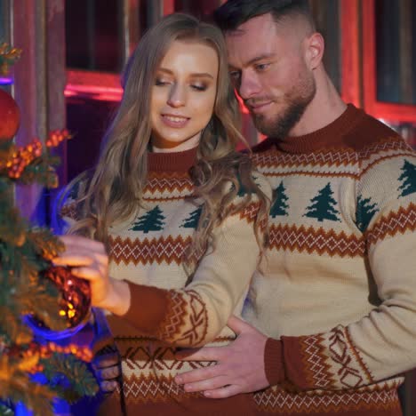 handsome man and beautiful woman decorate new year tree with christmas balls. spanding holidays together