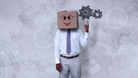 Businessman-wearing-smiley-face-box-pointing-on-cogwheel-