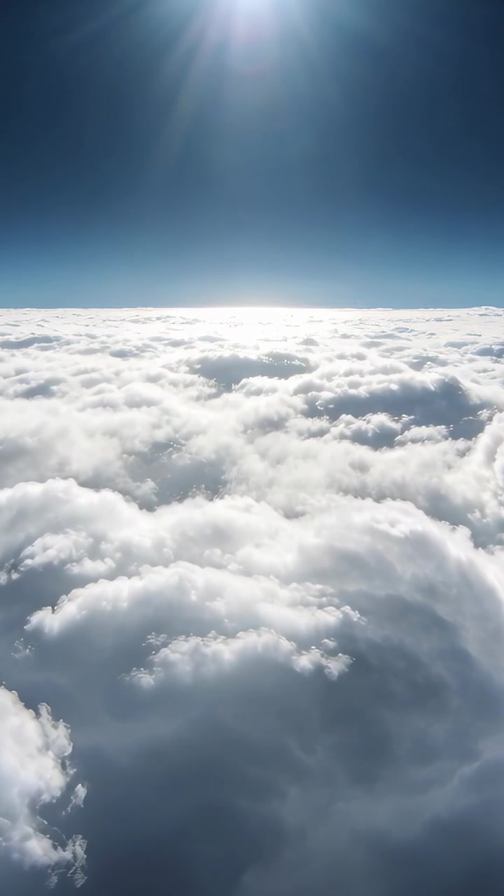 Video verticale: Telecamera in movimento che si avvicina a uno strato di cumuli sopra il cielo blu, rivelando il sole e l'orizzonte.