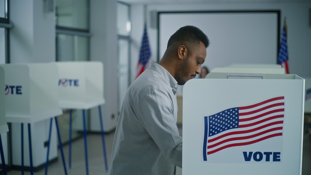 African American Man Takes Paper Ballot and Walks to Voting Booth African American Man Takes Paper Ballot from Female Polling Officer at Polling Station and Walks to Voting Booth National Election Day in the United States of America Civic Duty and Democracy