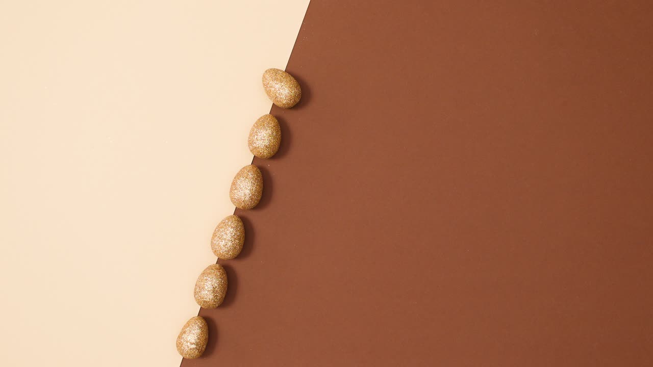 el concepto de colocación plana mínima del brillo de pascua los huevos de oro aparecen en un fondo marrón desnudo.