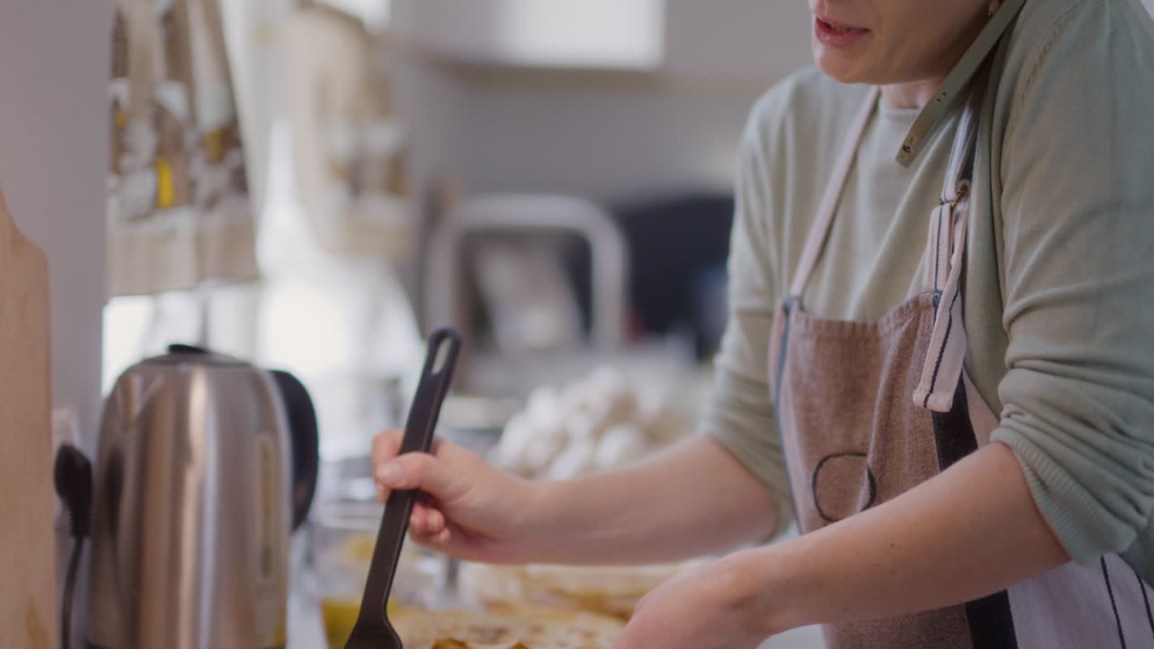 mujer hablando por teléfono mientras prepara la cena en la cocina está ocupada