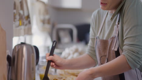 woman talking on phone while preparing dinner in kitchen is busy