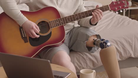 hombre talentoso con pierna protésica tocando la guitarra acústica